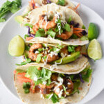 Top view of prawn tacos on a plate with creamy dressing.