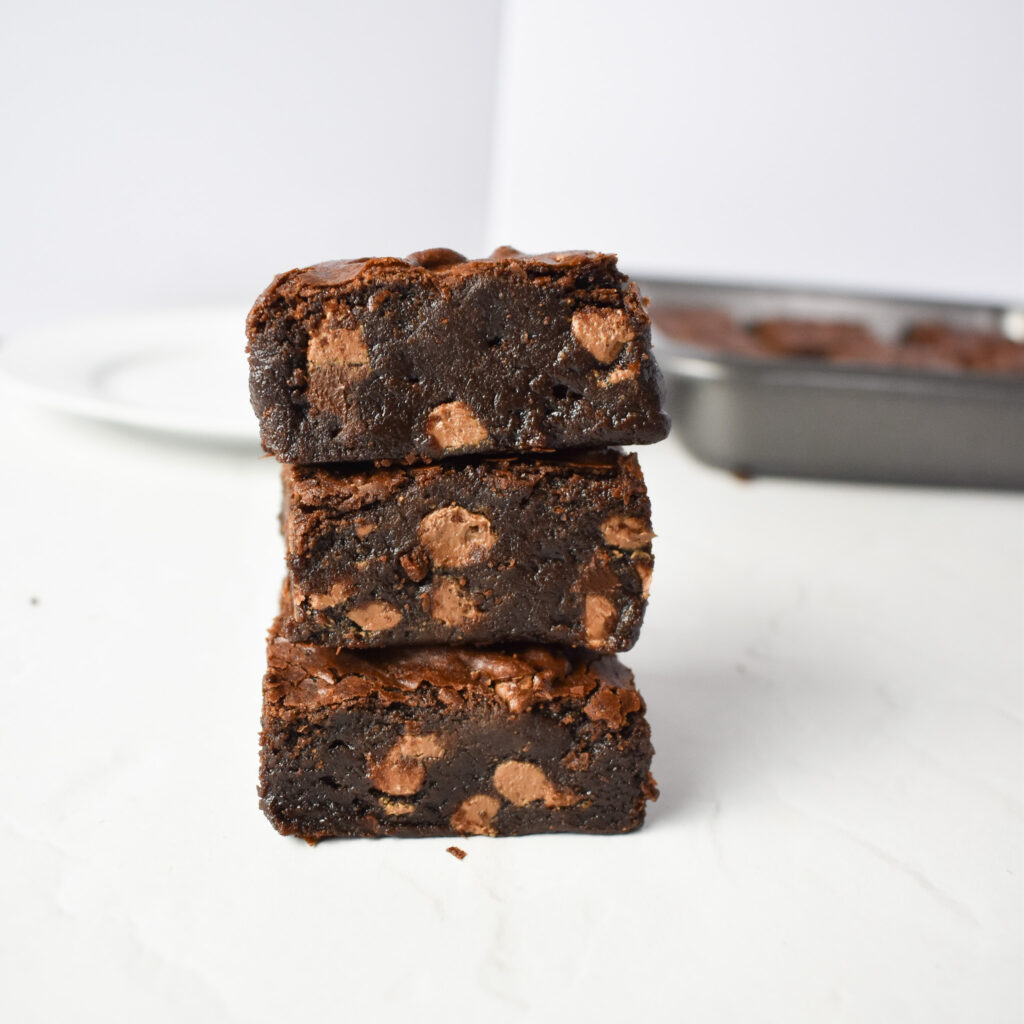 Fudgy Brownies with plate and baking tray in background.