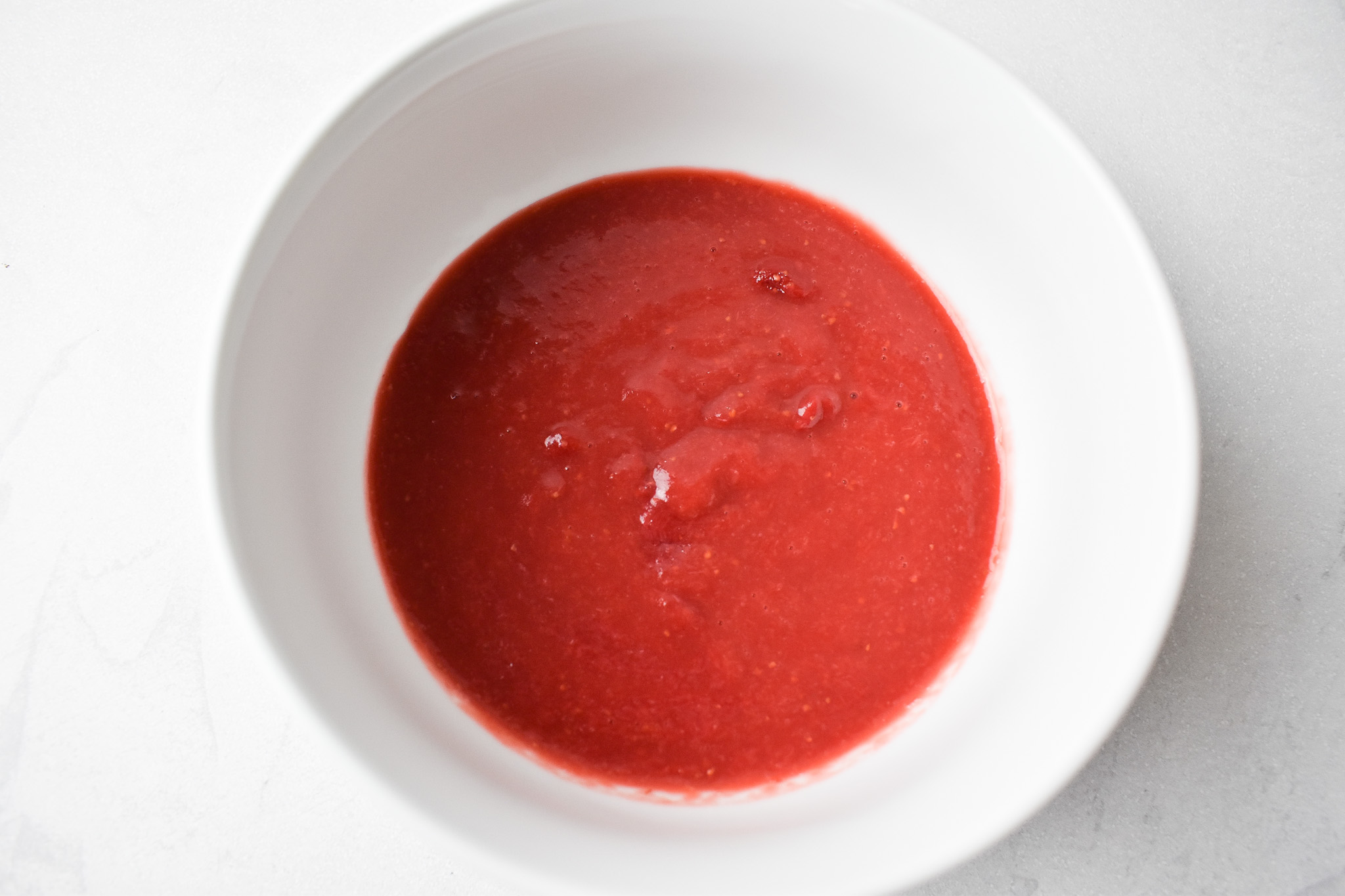 Reduced strawberries in a white bowl.
