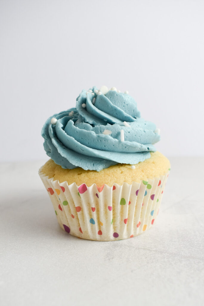 Single vanilla cupcake with blue buttercream frosting.